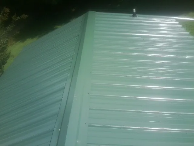 New green metal panels meeting at the ridge of a roof — Flat Roof Repair work by our crew in Danville